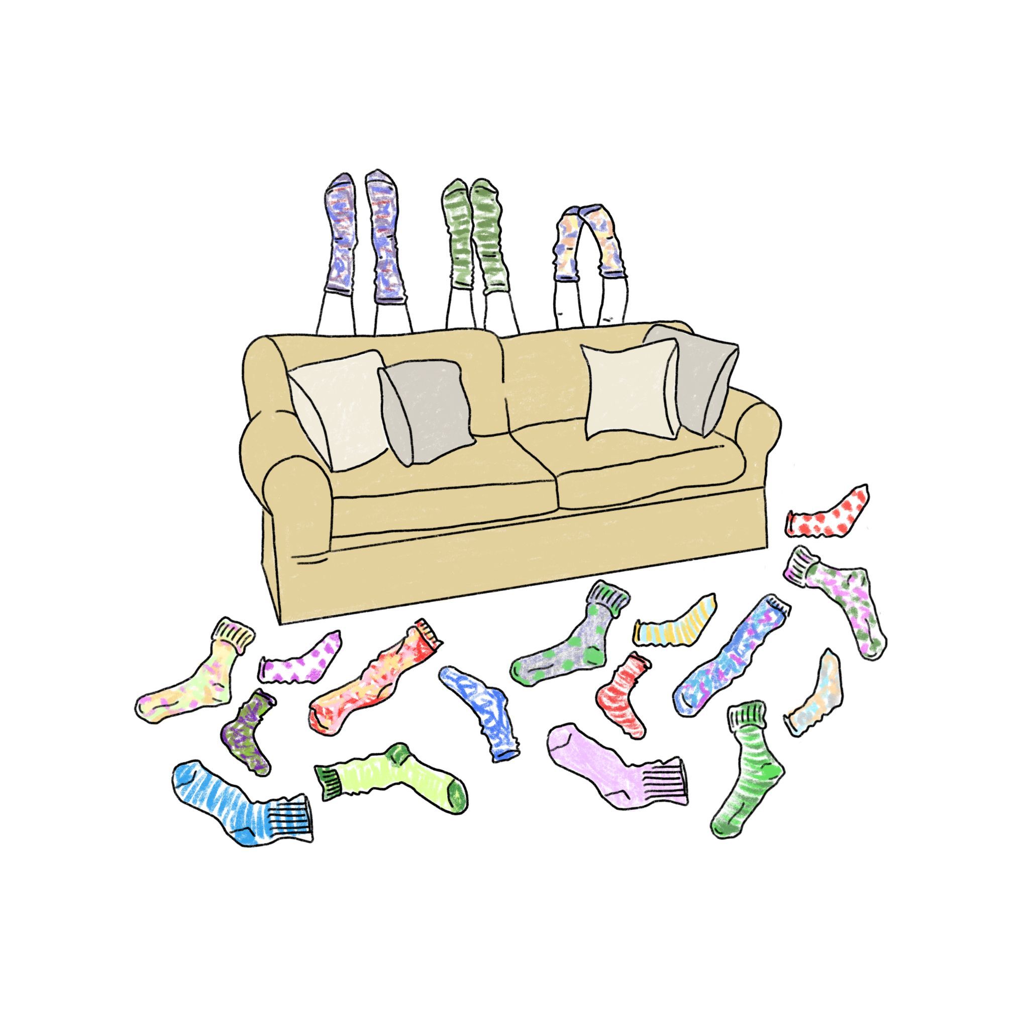 Bunte selbstgestrickte Socken liegen verstreut vor einem Sofa, weitere Socken hängen über die Rückenlehne